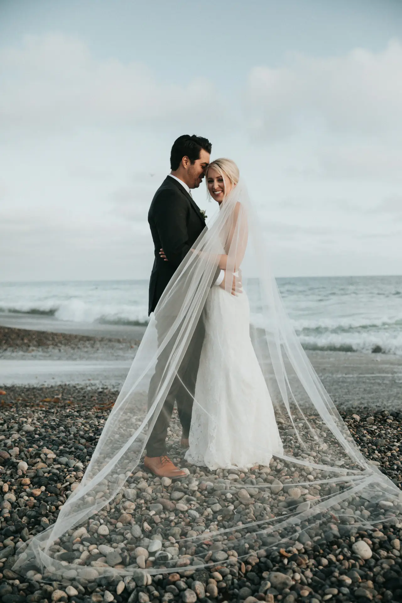 Couple on the beach with a long veil